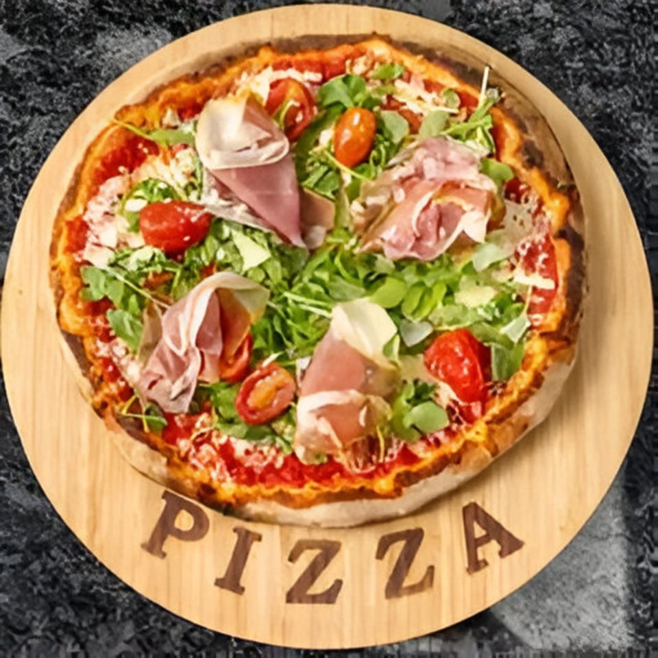 Bella Ciao pizza with prosciutto, arugula, and cherry tomatoes on a wooden board.
