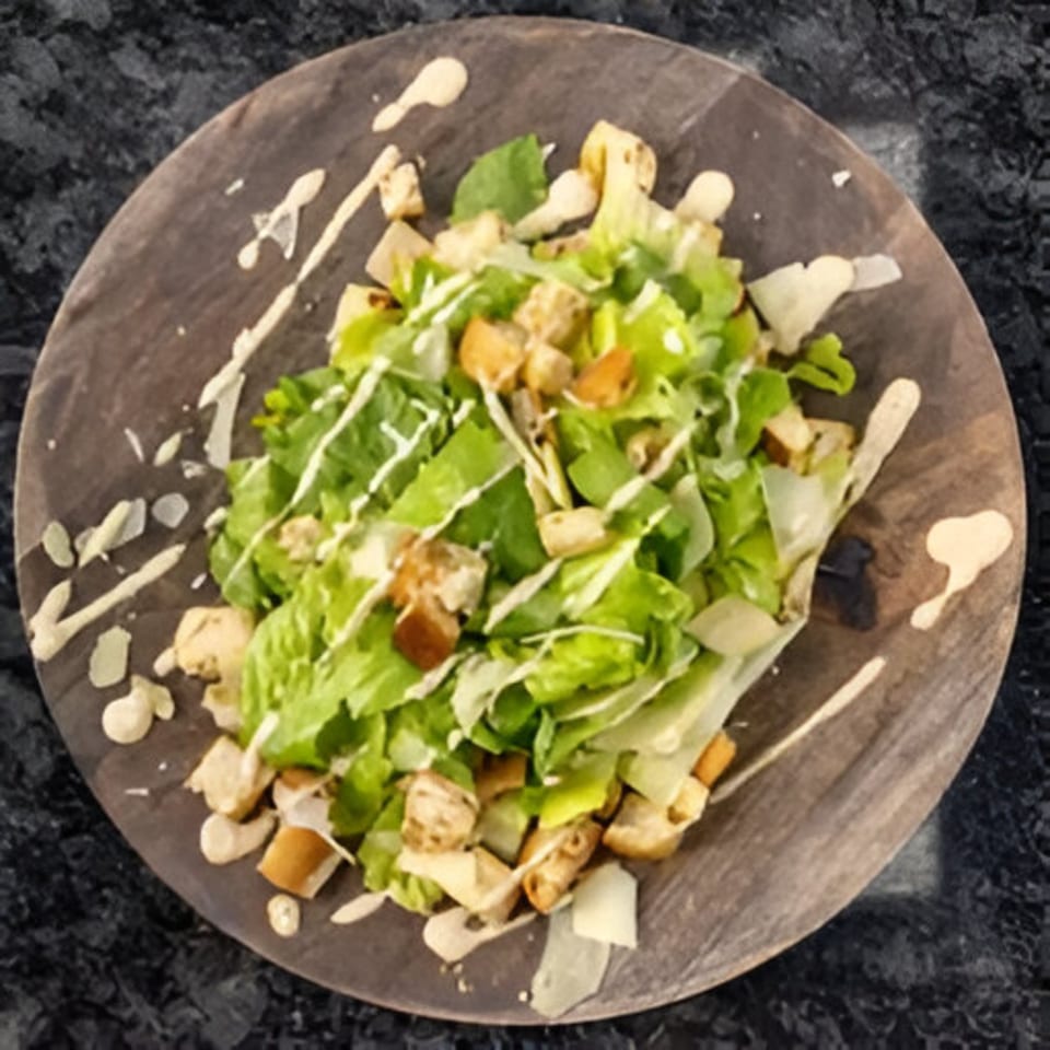 Caesar salad with crisp romaine lettuce, croutons, parmesan, and creamy dressing on a wooden plate.
